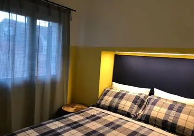 a bedroom with a bed with a checkered blanket and a window at NA' SCICCHERIA HOME in Castellammare del Golfo