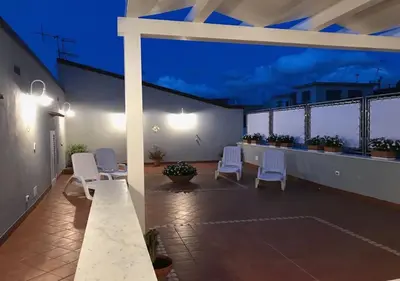 a rooftop patio with white chairs and a table at NA' SCICCHERIA HOME in Castellammare del Golfo
