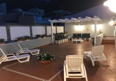 a patio with white chairs and a pergola at NA' SCICCHERIA HOME in Castellammare del Golfo