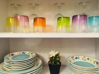 a shelf filled with colorful glass dishes and a plant at Around Cassaro Holiday House in Palermo