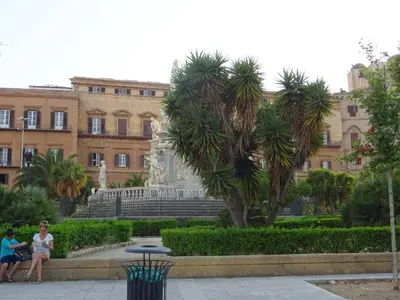 two women sitting on a bench in front of a building at Around Cassaro Holiday House in Palermo