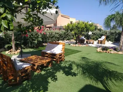a garden with chairs and tables on a lawn at L'isola del sole in Castelluzzo