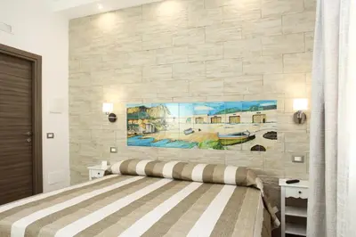 a bedroom with a bed with a painting on the wall at Ninni e Fede in San Vito lo Capo