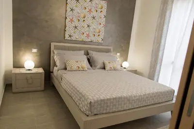 a bedroom with a bed with two tables and a painting at Casa Vacanze Fontana in San Vito lo Capo