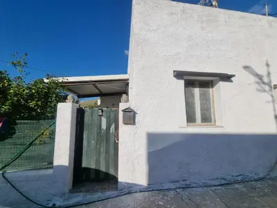 a white building with a gate and a window at Casa turiddu Makari in Castelluzzo