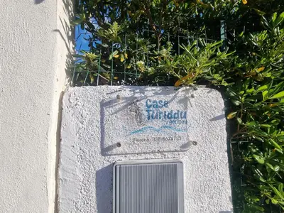 a sign on the side of a wall with plants at Casa turiddu Makari in Castelluzzo