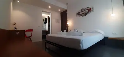 a bedroom with a bed with white sheets and a red chair at Patio 101 