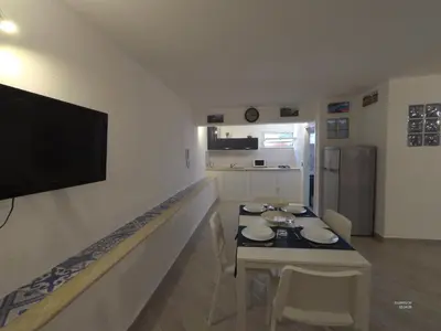 a living room with a table and a television on a wall at la petit maison in Palermo