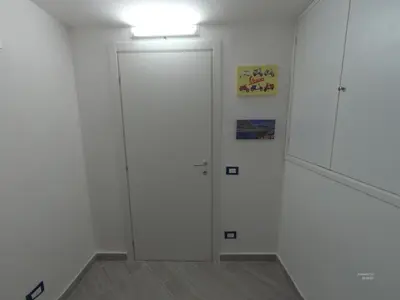 a white hallway with a door and a cabinet at la petit maison in Palermo