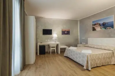 a hotel room with two beds and a desk at Le Vele di Balestrate in Balestrate