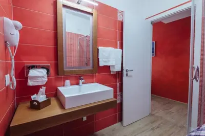 a red bathroom with a sink and a mirror at Le Vele di Balestrate in Balestrate