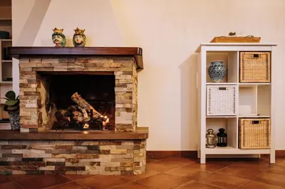 a living room with a stone fireplace and a shelf at Villa Zabbara Capo Zafferano in Bagheria
