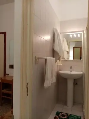 a white bathroom with a sink and a mirror at Ariston Petit Hotel in Palermo
