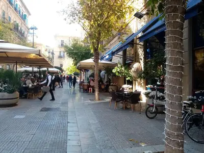 a street with tables and chairs and people walking down the street at Ariston Petit Hotel in Palermo