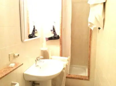 a bathroom with a sink and a toilet and a mirror at Ariston Petit Hotel in Palermo