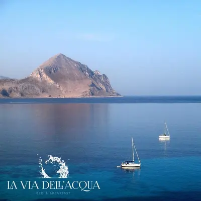 two boats in the water with a mountain in the background at La Via dell'Acqua in Macari