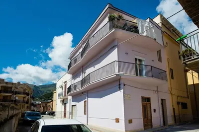 a white building with a balcony on a street at Casa Mariú in Castellammare del Golfo