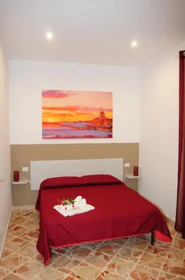 a bedroom with a red bed with a painting on the wall at I Paesaggi in Castellammare del Golfo