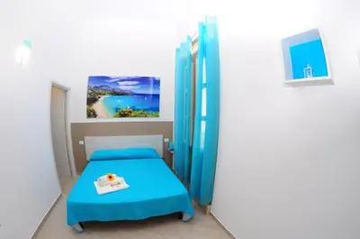 a small bedroom with a blue bed and a painting at I Paesaggi in Castellammare del Golfo