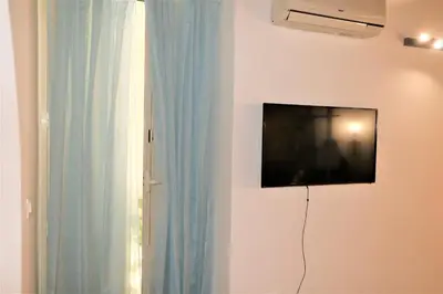 a flat screen tv hanging on a wall next to a window at Palermo Home White Home in Palermo