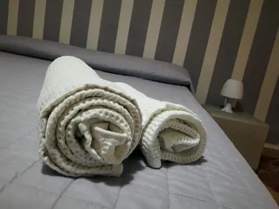 a rolled up white blanket on a bed at Al Civico 8 - Palermo in Palermo