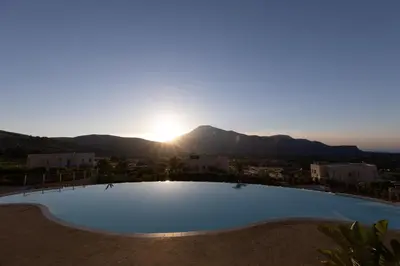 a large swimming pool with the sunset in the background at Villa Cristina - Relax - Piscina e Vista Mare in Castellammare del Golfo