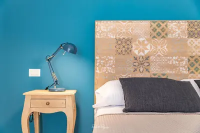 a bed with a lamp on a table next to a blue wall at Sweet Roma 315 in Palermo