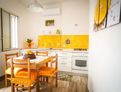 a kitchen with a table and chairs and yellow tiles at Baglio Reale Apartments in Palermo