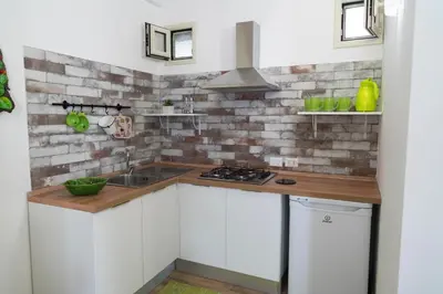 a kitchen with white cabinets and a brick wall at Baglio Reale Apartments in Palermo