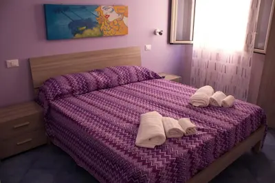 a bedroom with a purple bed with towels on it at Affittacamere da Noemi in Castellammare del Golfo
