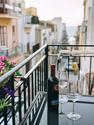 a bottle of wine and two wine glasses on a balcony at Affittacamere da Noemi in Castellammare del Golfo