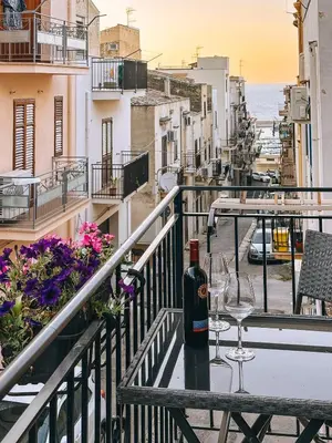 a table with a bottle of wine and glasses on a balcony at Affittacamere da Noemi in Castellammare del Golfo