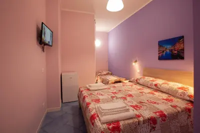 a bedroom with two beds and a tv on the wall at Affittacamere da Noemi in Castellammare del Golfo