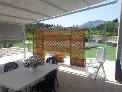 a patio with a table and chairs and a fence at Villa Verde in Alcamo