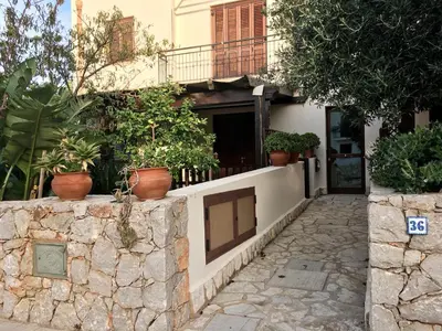 a building with potted plants on a stone wall at Appartamento BluOltreMare in San Vito lo Capo