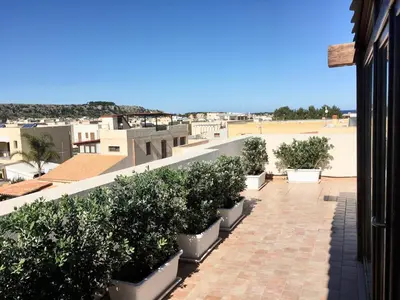 a balcony with potted plants on a building at Appartamento BluOltreMare in San Vito lo Capo