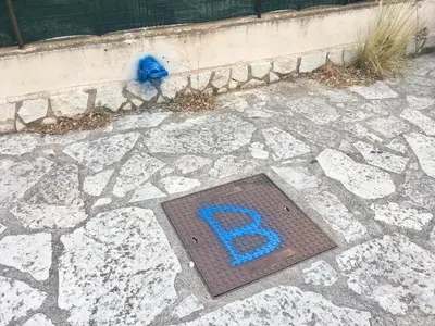 a metal grate with a letter r on the ground at Appartamento BluOltreMare in San Vito lo Capo