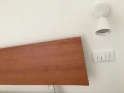 a light on a white wall with a wooden board at YooRoom in Palermo