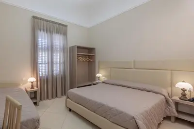 a bedroom with two beds and a window and two lamps at Ghibli Hotel in San Vito lo Capo