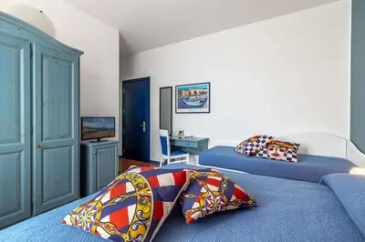 a bedroom with two beds and a tv at Ghibli Hotel in San Vito lo Capo