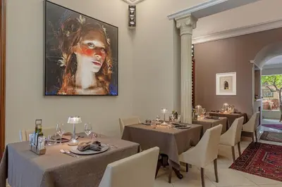 a dining room with tables and a painting on the wall at Ghibli Hotel in San Vito lo Capo