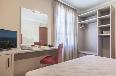 a bedroom with a desk with a computer and a red chair at Ghibli Hotel in San Vito lo Capo