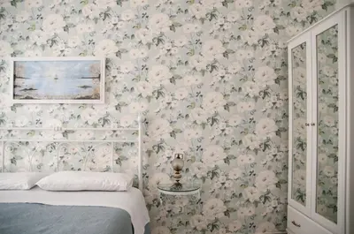 a bedroom with floral wallpaper and a bed with a bedspread at Ai Mori in Palermo