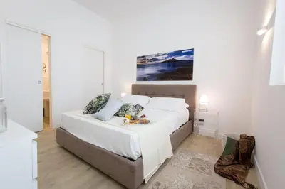 a bedroom with a white bed with a painting on the wall at Palermo In Suite Aparthotel in Palermo