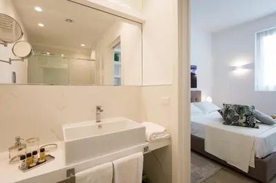 a white bathroom with a sink and a bed at Palermo In Suite Aparthotel in Palermo