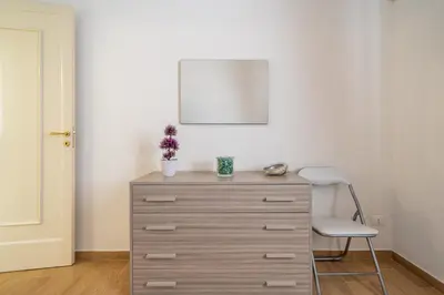 a dresser in a room with a chair and a mirror at Le Casette Di Maria Pia in Mondello
