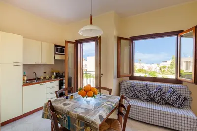 a kitchen and dining room with a table and a couch at Residence Smeraldo in San Vito lo Capo