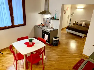 a kitchen and living room with a table and red chairs at WelcHomeLoft in Palermo