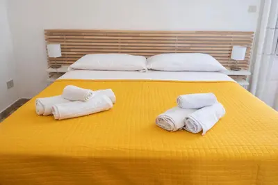 a bedroom with two beds with towels on a yellow blanket at Casa Lisa a due passi dal mare con ampio giardino in San Vito lo Capo