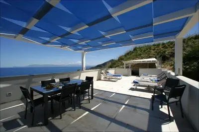 a patio with a blue roof with a table and chairs at Villa Antonia - Vasca Idromassaggio Terrazza Vista Mare in San Vito lo Capo